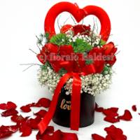 Composizione in scatola nera con rose rosse e cuori decorativi